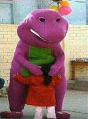 a purple dinosaur mascot embracing a small child outdoors